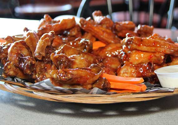 Picture of a plate of sauced wings and carrot sticks.